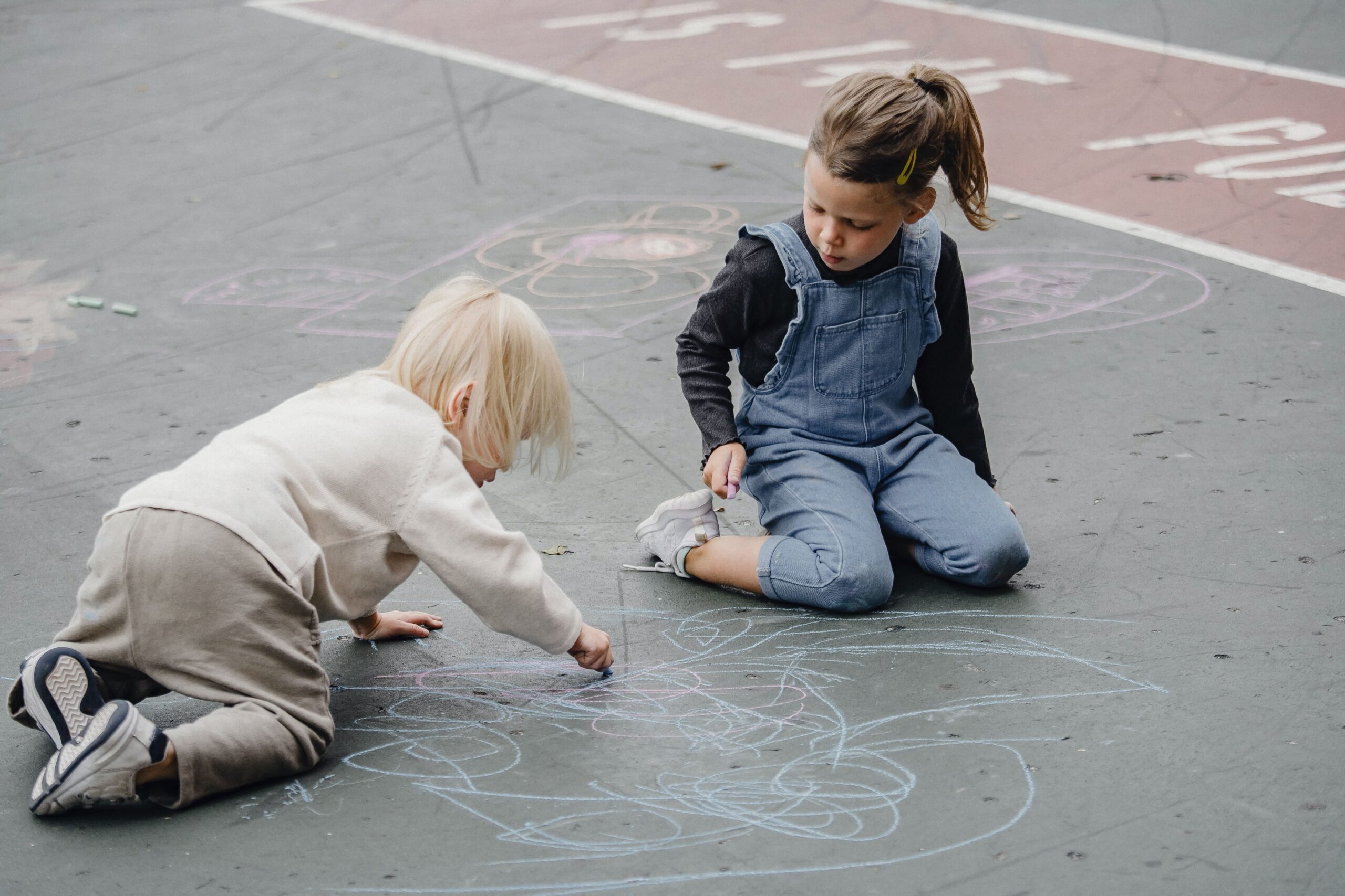Deux enfants en train de dessiner sur le sol